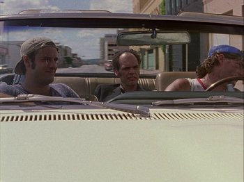 Movie still from “Slacker” (1990), directed by Richard Linklater – A group of people in a car driving down a street; Medium shot, Low angle