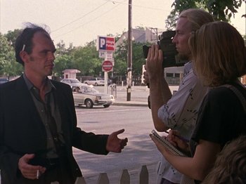 Movie still from “Slacker” (1990), directed by Richard Linklater – A man talking to two women on the side of the road; Medium shot, Over the shoulder angle
