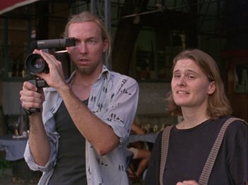 Movie still from “Slacker” (1990), directed by Richard Linklater – A man and a woman holding a video camera; Close Up shot, Low angle