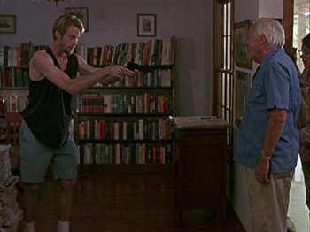 Movie still from “Slacker” (1990), directed by Richard Linklater – A man holding a camera in a room with a man standing in front of him; Medium shot, Over the shoulder angle