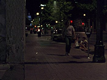 Movie still from “Slacker” (1990), directed by Richard Linklater – A woman walking down the sidewalk at night; Wide shot, High angle