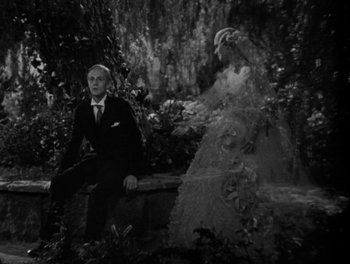 Movie still from “Smilin' Through” (1932), directed by Sidney Franklin – A man and a woman sitting next to each other on top of a bench; Wide shot, Over the shoulder angle