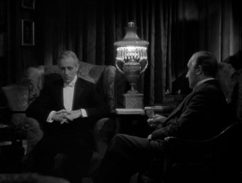 Movie still from “Smilin' Through” (1932), directed by Sidney Franklin – Two men in suits sitting in a living room next to each other; Medium shot, High angle