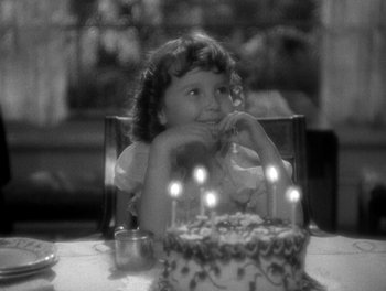 Movie still from “Smilin' Through” (1932), directed by Sidney Franklin – A little girl sitting in front of a birthday cake; Close Up shot, High angle