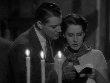 Movie still from “Smilin' Through” (1932), directed by Sidney Franklin – A man and a woman standing next to lit candles; Medium shot, High angle