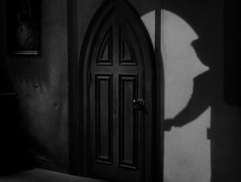 Movie still from “Smilin' Through” (1932), directed by Sidney Franklin – A black and white photo of a door and shadow; Wide shot, Low angle