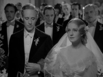 Movie still from “Smilin' Through” (1932), directed by Sidney Franklin – A black and white photo of a man and woman in front of a crowd; Medium shot, High angle