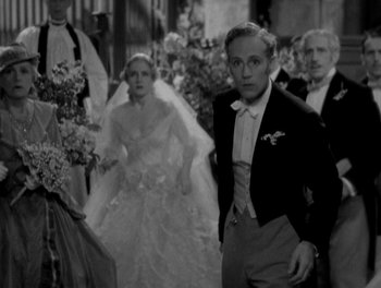 Movie still from “Smilin' Through” (1932), directed by Sidney Franklin – A black and white photo of a man and a woman in formal wear; Medium shot, High angle