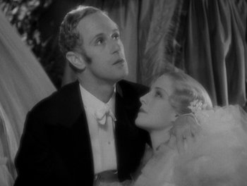Movie still from “Smilin' Through” (1932), directed by Sidney Franklin – A man and a woman in formal wear posing for a picture; Close Up shot, Low angle