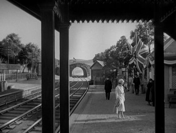 Movie still from “Smilin' Through” (1932), directed by Sidney Franklin – A black - and - white photo of people at a train station; Wide shot, High angle