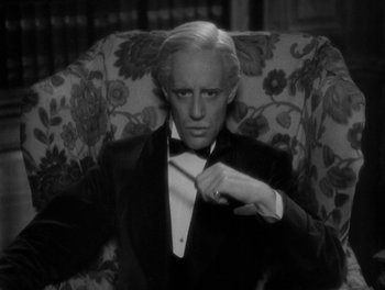 Movie still from “Smilin' Through” (1932), directed by Sidney Franklin – A black and white photo of a man in a suit and bow tie; Close Up shot, High angle