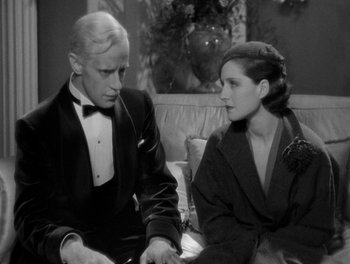Movie still from “Smilin' Through” (1932), directed by Sidney Franklin – A man and a woman sitting next to each other on a couch; Medium shot, Over the shoulder angle