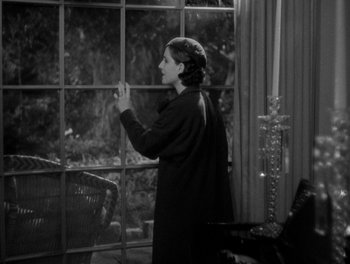 Movie still from “Smilin' Through” (1932), directed by Sidney Franklin – A black and white photo of a woman looking out of a window; Medium shot, High angle