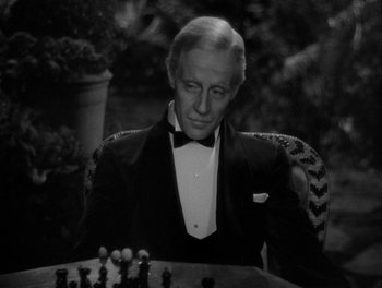 Movie still from “Smilin' Through” (1932), directed by Sidney Franklin – A man in a tuxedo sitting in front of a chessboard; Close Up shot, High angle
