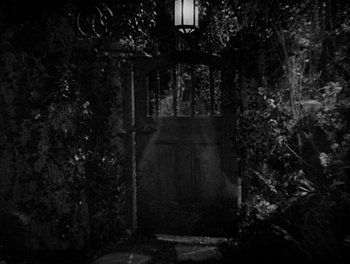 Movie still from “Smilin' Through” (1932), directed by Sidney Franklin – A black - and - white photo of a gate in a garden; Wide shot, High angle