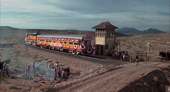 Movie still from “Smokey and the Bandit II” (1980), directed by Hal Needham – People are standing on the side of a train track; Extreme Wide shot, High angle