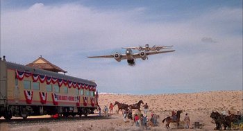 Movie still from “Smokey and the Bandit II” (1980), directed by Hal Needham – An airplane is flying low over a group of people; Extreme Wide shot, Low angle