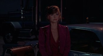 Movie still from “Smokey and the Bandit II” (1980), directed by Hal Needham – A woman in a red jacket standing next to a car; Medium shot, Over the shoulder angle
