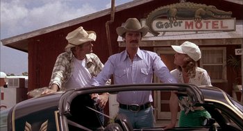 Movie still from “Smokey and the Bandit II” (1980), directed by Hal Needham – A group of people standing next to each other in front of a building; Medium shot, Low angle