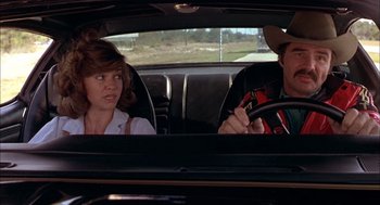 Movie still from “Smokey and the Bandit II” (1980), directed by Hal Needham – A man and a woman sitting in the back of a car; Medium shot, Over the shoulder angle