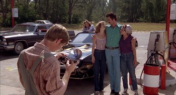 Movie still from “Smokey and the Bandit II” (1980), directed by Hal Needham – A group of people standing next to each other near a car; Wide shot, Over the shoulder angle