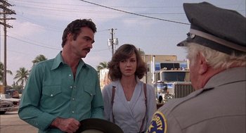 Movie still from “Smokey and the Bandit II” (1980), directed by Hal Needham – A man and a woman standing next to each other; Medium shot, Over the shoulder angle