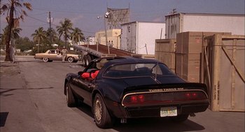 Movie still from “Smokey and the Bandit II” (1980), directed by Hal Needham – A black sports car is driving down the street; Wide shot, Over the shoulder angle