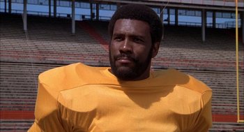 Movie still from “Smokey and the Bandit II” (1980), directed by Hal Needham – An african american football player in a yellow uniform; Close Up shot, Low angle