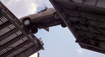 Movie still from “Smokey and the Bandit II” (1980), directed by Hal Needham – A car that is hanging off the side of a bridge; Wide shot, Overhead angle