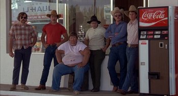 Movie still from “Smokey and the Bandit II” (1980), directed by Hal Needham – A group of men standing next to each other on the street; Wide shot, Low angle