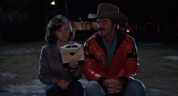 Movie still from “Smokey and the Bandit II” (1980), directed by Hal Needham – A man and a woman sitting next to each other; Medium shot, Over the shoulder angle