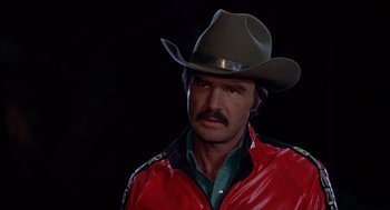 Movie still from “Smokey and the Bandit II” (1980), directed by Hal Needham – A man wearing a cowboy hat and a red jacket; Close Up shot, Over the shoulder angle