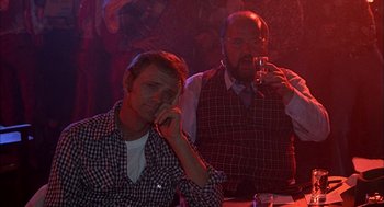 Movie still from “Smokey and the Bandit II” (1980), directed by Hal Needham – Two men sitting at a table in front of a red light; Medium shot, Over the shoulder angle