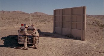 Movie still from “Smokey and the Bandit II” (1980), directed by Hal Needham – A couple of men standing next to each other on top of a dirt field; Extreme Wide shot, Low angle
