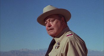 Movie still from “Smokey and the Bandit II” (1980), directed by Hal Needham – An older man wearing a hat and a uniform; Close Up shot, Low angle