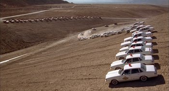 Movie still from “Smokey and the Bandit II” (1980), directed by Hal Needham – A group of trucks parked on top of a dirt field; Extreme Wide shot, High angle