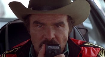 Movie still from “Smokey and the Bandit II” (1980), directed by Hal Needham – A man in a cowboy hat taking a picture with a cell phone; Close Up shot, Low angle