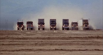 Movie still from “Smokey and the Bandit II” (1980), directed by Hal Needham – A group of trucks driving down a dirt road; Extreme Wide shot, Low angle