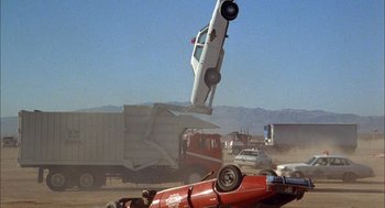 Movie still from “Smokey and the Bandit II” (1980), directed by Hal Needham – A car that is falling off of a truck; Wide shot, Low angle