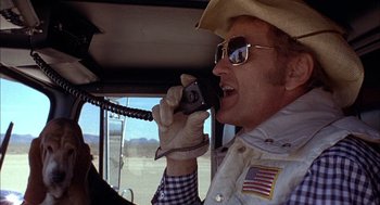 Movie still from “Smokey and the Bandit II” (1980), directed by Hal Needham – A man talking on a cell phone while sitting in a vehicle; Close Up shot, Low angle