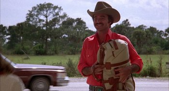 Movie still from “Smokey and the Bandit II” (1980), directed by Hal Needham – A man in a cowboy hat holding a suitcase; Medium shot, Low angle