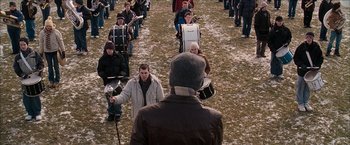 Movie still from “Snow Angels” (2007), directed by David Gordon Green – A group of people standing in a field playing instruments; Extreme Wide shot, High angle