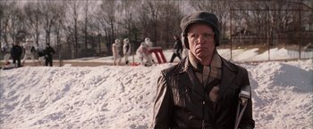 Movie still from “Snow Angels” (2007), directed by David Gordon Green – An older man wearing a hat and glasses in the snow; Medium shot, Over the shoulder angle