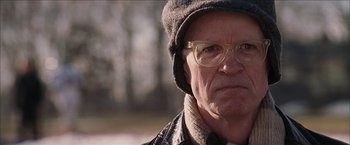 Movie still from “Snow Angels” (2007), directed by David Gordon Green – An older man wearing glasses and a hat; Close Up shot, Over the shoulder angle