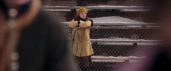 Movie still from “Snow Angels” (2007), directed by David Gordon Green – A woman wearing a yellow coat and a yellow hat; Medium shot, Over the shoulder angle