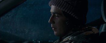 Movie still from “Snow Angels” (2007), directed by David Gordon Green – A young man wearing a winter hat looking to his left; Close Up shot, Over the shoulder angle