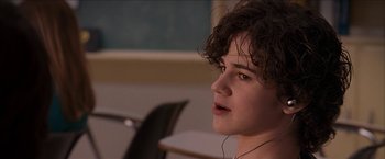 Movie still from “Snow Angels” (2007), directed by David Gordon Green – A young man with headphones is listening intently to music; Close Up shot, Over the shoulder angle