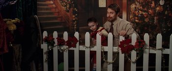 Movie still from “Snow Angels” (2007), directed by David Gordon Green – A man and a child in front of a white picket fence; Medium shot, Over the shoulder angle
