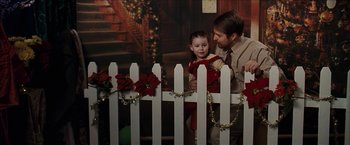 Movie still from “Snow Angels” (2007), directed by David Gordon Green – A man and a child standing next to a white picket fence; Medium shot, Over the shoulder angle