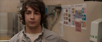 Movie still from “Snow Angels” (2007), directed by David Gordon Green – A young man with long brown hair is looking at the camera; Close Up shot, Over the shoulder angle